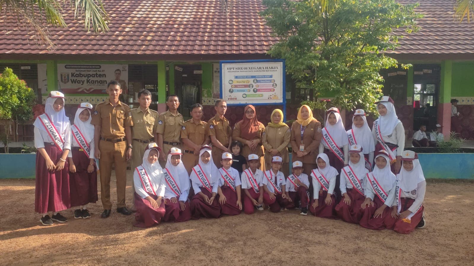 Guru dan siswa petugas upacara berfoto bersama di depan gedung UPT SDN 01 Negara Harja.